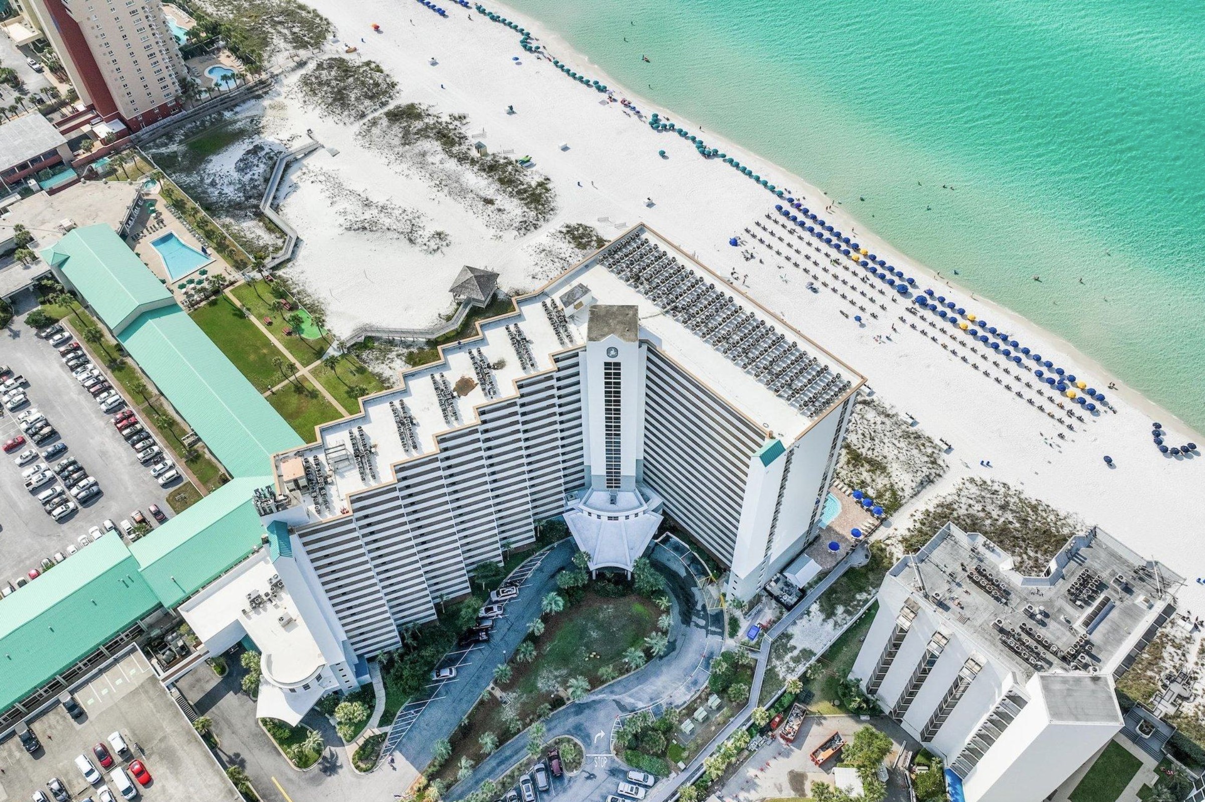 Aerial view of Pelican Beach Resort, its Gulf-front building, pools, beach and Gulf of Mexico in Destin